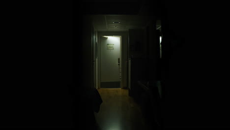 Young-Man-leaving-dark-hotel-room,-not-looking-back-while-door-shuts,-slow-motion
