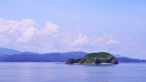 Passing-Island-with-Mountains-on-the-Horizon-in-Costa-Rican-Landscape-on-Sunny-Day-with-cloudy-Sky,-Full-Shot