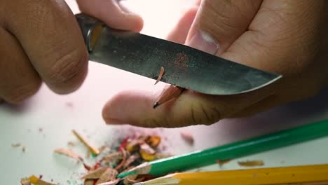 Footage-of-hands-slowly-sharpening-a-pencil-and-some-coloured-pencils-with-a-sharp-knife