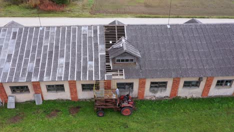 Construction-in-progress-renovating-asbestos-barn-roof,-overhead-aerial-approach