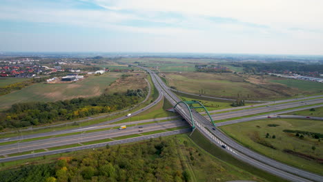 Aerial-Rise-Up-View-of-Cars-Traffic-on-Countryside-Highway-Interchange-Intersection-in-Straszyn-Gdansk-Poland,-Nature-Suburban-Surroundings