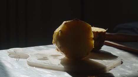 Hand-putting-pineapple-on-a-chopping-board,-close-up,-slow-motion