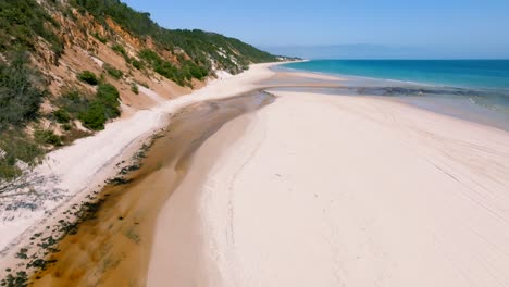A-river-meets-the-ocean-while-the-drone-is-revealing-the-endless-pristine-beaches-of-Fraser-Island-on-a-sunny-day