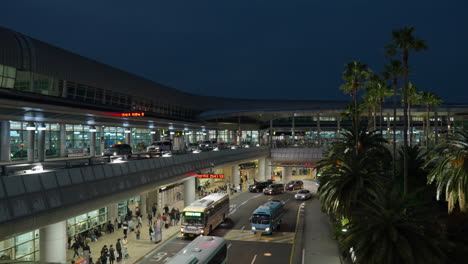Autobuses-Y-Automóviles-Conduciendo-De-Noche-Con-Pasajeros-Esperando-En-El-Punto-De-Entrega-Y-Recogida-Del-Aeropuerto-Internacional-De-Jeju-En-Corea-Del-Sur