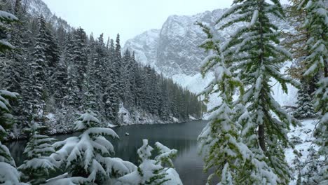 Peekaboo-view-of-high-cascade-mountain-lake-while-it's-snowing-on-larches