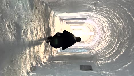 POV-Walking-Behind-Person-Walking-Through-Ice-Carved-Ice-Tunnel-At-Ice-Hotel-Towards-Light