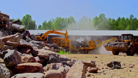 JCB-Bulldozer-engaged-in-collecting-stones,-crushing-it-and-dumping-it-on-the-other-side,-static-shot