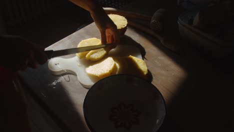 hands-slicing-pineapple,-and-putting-them-into-a-bowl