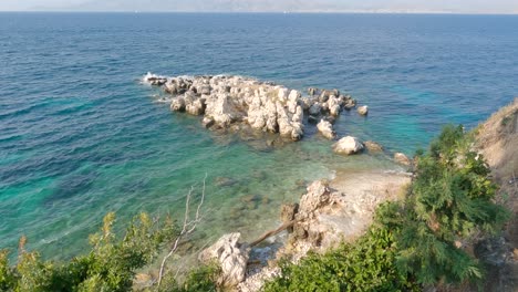 View-Looking-Down-At-Tree-Overlooking-Rocky-Shoreline-With-Turquoise-Waters-At-Kassiopi