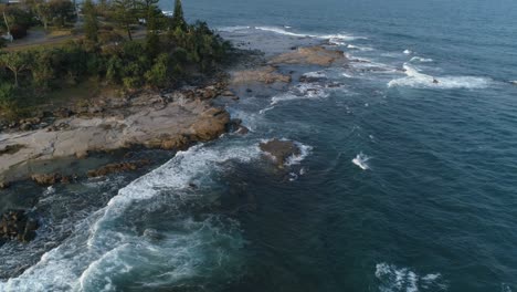 Aerial-shot-of-waves-crashing-on-rocks