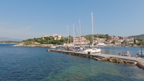Panning-shot-of-Kassiopi-port-with-sail-boats-docked,-Corfu