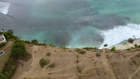 Vuela-Un-Dron-Hacia-Atrás-Sobre-El-Océano-índico-Filmando-Grandes-Olas-Y-La-Colina-De-La-Playa-De-Dreamland-En-Bali,-Indonesia