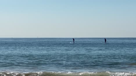 two-Young-mans-are-standing-on-a-swimming-board-and-paddling-in-Cascais