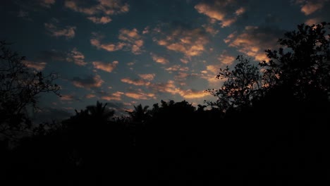Dramatische-Wolken,-Die-Das-Sonnenlicht-Mit-Dunklen-Silhouetten-Tropischer-Bäume-Reflektieren