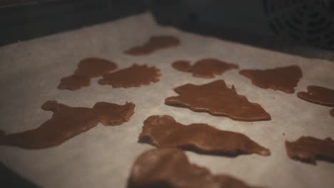 Zooming-out-gingerbread-cookies-being-baked-in-the-oven-on-a-paper-covered-oven-plate