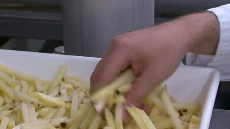 Hände-Greifen-Zurückgewiesene-Pommes-Frites-In-Einer-Lebensmittelfabrik