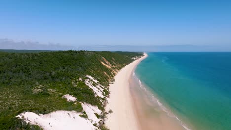 Drone-footage-from-the-remote-side-of-Fraser-Island's-incredible-shoreline,-aqua-toned-water-and-colorful-sand-dunes