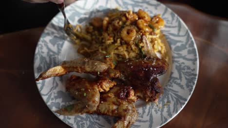 Birds-Eye-View-Of-Fork-Tucking-Into-Fried-Prawns-With-Pasta-And-BBQ-Chicken-On-Plate