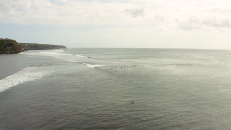 Cinematic-drone-forward-fly-capturing-surfers-on-surfboard-waiting-for-big-waves