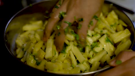 Diced-Pineapple-Pieces-Being-Mixed-With-Cilantro,-Salt-And-Green-Chillies-In-Metal-Bowl