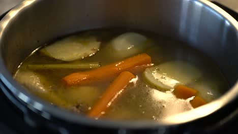 Healthy-chicken-soup-in-pot-cooking-and-bubbling-with-vegetables-floating