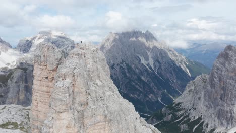 Hiker-stands-on-summit-of-rugged-Torre-di-Toblin,-Dolomites