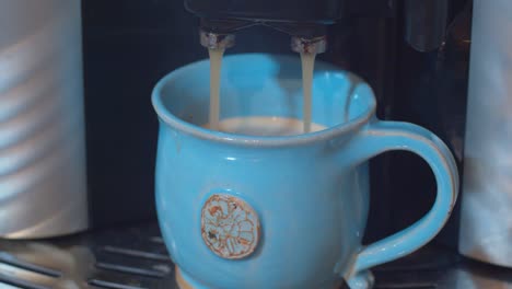 Espresso-coffee-going-from-bean-to-cup-machine-into-blue-handmade-cup