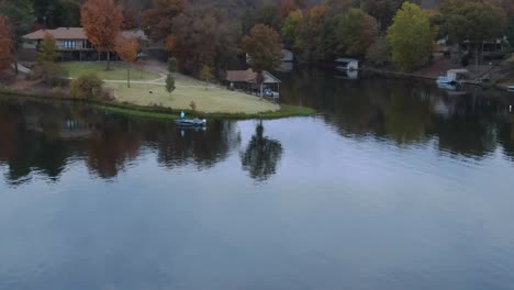 Low-altitude-aerial-view-of-bass-fisherman-in-boat-along-shore-of-retirement-community-lake