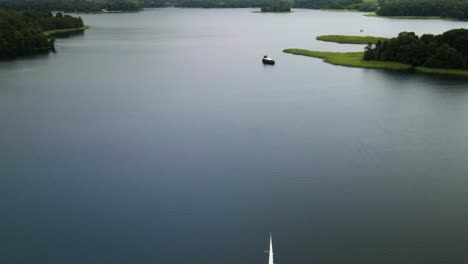 aerial-shot-of-a-sailing-yacht-in-Galves-lake-in-Trakai,-in-Lithuania