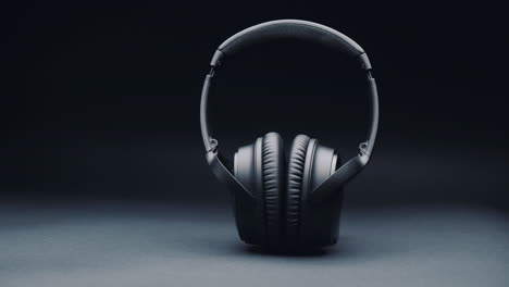 A-product-shot-of-black-headphones-on-a-black-background,-standing-upright