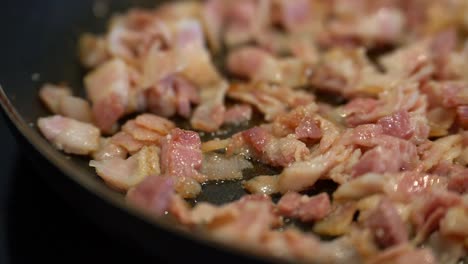 Diced-fat-bacon-slices-sizzle-and-bubble-in-fry-pan,-cinematic-cooking-close-up