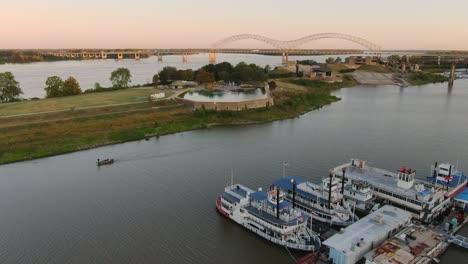 Aerial-view-above-small-fishing-boat-passing-along-the-Mississippi-river-with-docked-paddle-boats