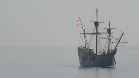 Ferdinand-Magellan-Nao-Victoria-carrack-boat-replica-with-spanish-flag-sails-in-the-mediterranean-at-sunrise-in-calm-sea-in-slow-motion-60fps