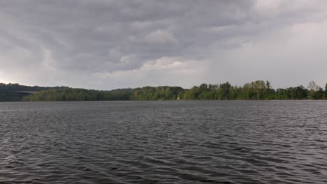 A-tilt-up-from-murky-lake-water-rippling-in-the-wind-to-reveal-storm-clouds