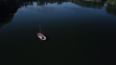 Drohne-Fliegt-über-Dunklen-Teich-In-Europa,-Während-Die-Sonne-Auf-Einem-Kleinen-Boot-Untergeht