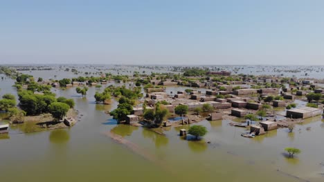 Vista-Panorámica-Aérea-De-Edificios-Rurales-Sumergidos-En-Agua-De-Inundación-En-Mehar,-Sindh,-Pakistán