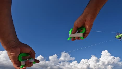 Unusual-perspective-of-hands-flying-green-kite-by-holding-green-handles