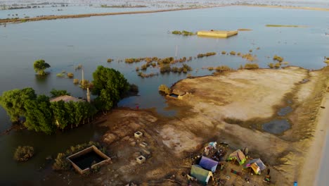 Aerial-Over-Makeshift-Tents-Beside-Road-With-Fields-Under-Water-Due-To-Flooding-In-Daharki