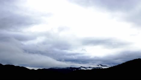 Time-lapse-of-clouded-sky-after-thunderstorm-over-the-mountain-range-in-the-morning-with-rays-of-sunrise