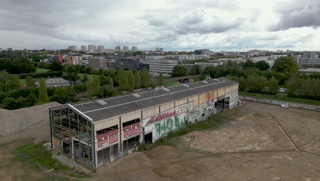 Exterior-of-old-abandoned-building-with-city-in-background,-urban-exploration-or-urbex