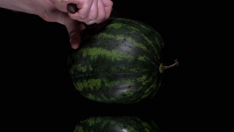 Mannhände-Schneiden-Wassermelone-Auf-Einem-Schwarzen-Bildschirm-In-Zwei-Hälften