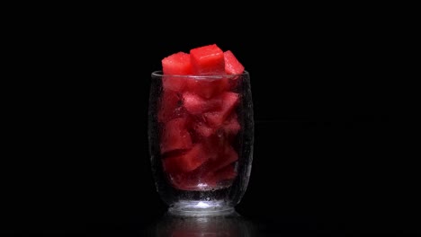 Glass-filled-with-watermelon-cubes,-water-dripping-from-it