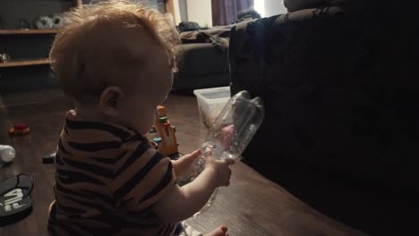 Kleines-Mädchen,-Das-Im-Wohnzimmer-Mit-Einer-Plastikwasserflasche-Spielt