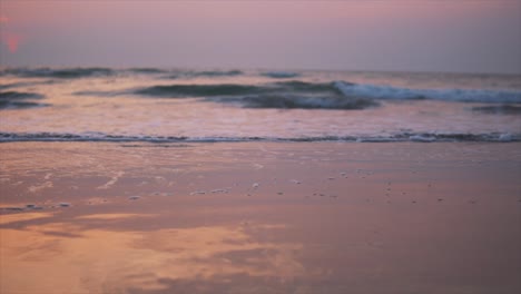 Wellen,-Die-An-Einem-Wunderschönen-Strand-Plätschern,-Der-Wegen-Des-Sonnenuntergangs-Orange-Und-Rosa-Wurde