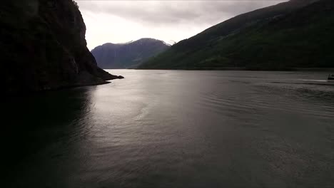 Hermosa-Toma-De-Drones-Volando-Sobre-El-Agua-Hacia-Las-Vistas-Panorámicas-De-Noruega-En-Un-Día-Nublado-Y-Sombrío