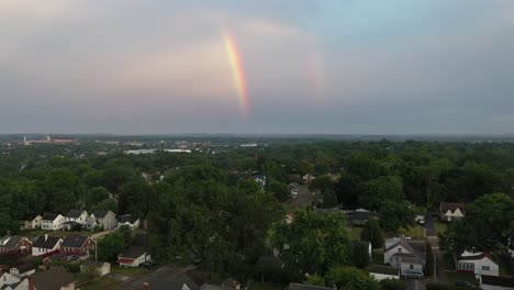 Drone-shot-of-a-rainbow-over-a-town-at-sunset