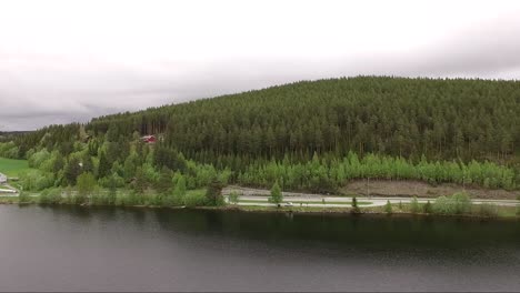 Tracking-forward-panoramic-drone-shot-of-Norway-landscape,-cloudy-skies-and-green-trees