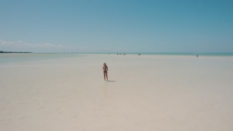Tracking-Shot-Of-Girl-Wearing-Bikini-Walking-On-Sandy-Beach-Under-Sun,-HOLBOX