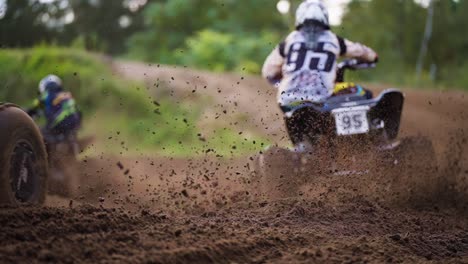 Quad-Bikers-Racing-Competition-on-Dirt-Muddy-Road-With-Mud-Scattering-Under-Wheels-in-Slow-motion