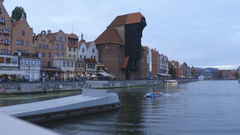 panning-shot-from-a-bridge-at-river-Martwa-Gdansk-Poland-Europe-,view-of-Crane-Zuraw-boat-with-tourists-and-traditional-architecture-buildings